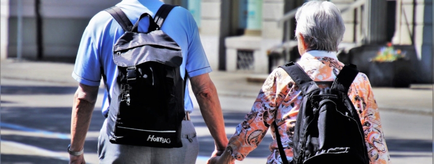 Senior couple with backpacks walking on the street