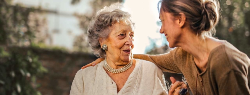 Joyful adult daughter greeting happy surprised senior mother in garden