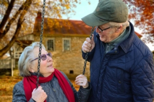 Senior man standing beside senior woman on swing