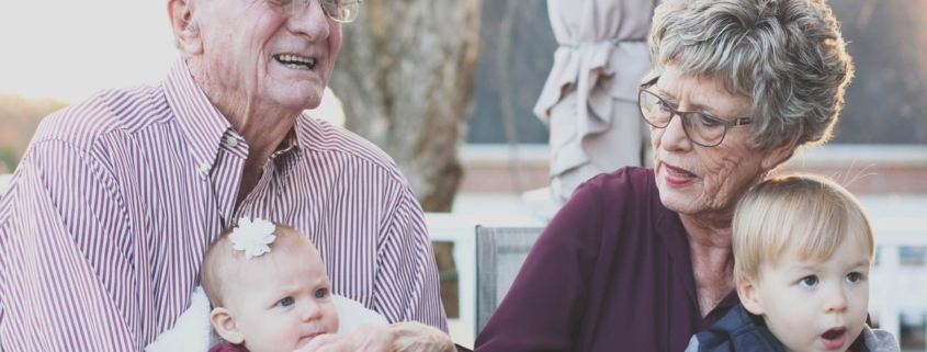 Grandmother and grandfather holding their grandchildren on their lap