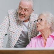 Elderly couple with eyeglasses talking in front of a laptop