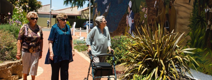 Elderly woman walking with a walker looking at a mural